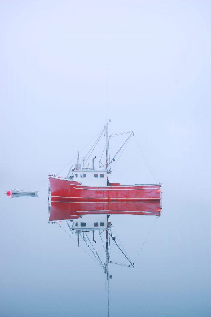 Red Fishing boat on misty lake New Brunswick, Canada.